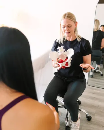 A She PT therapist showing a patient a pelvis model during an evaluation